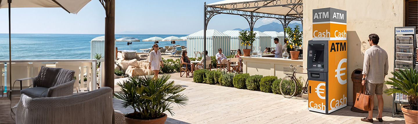 Distributeur de billets In2Retail en bord de mer, près d’une terrasse