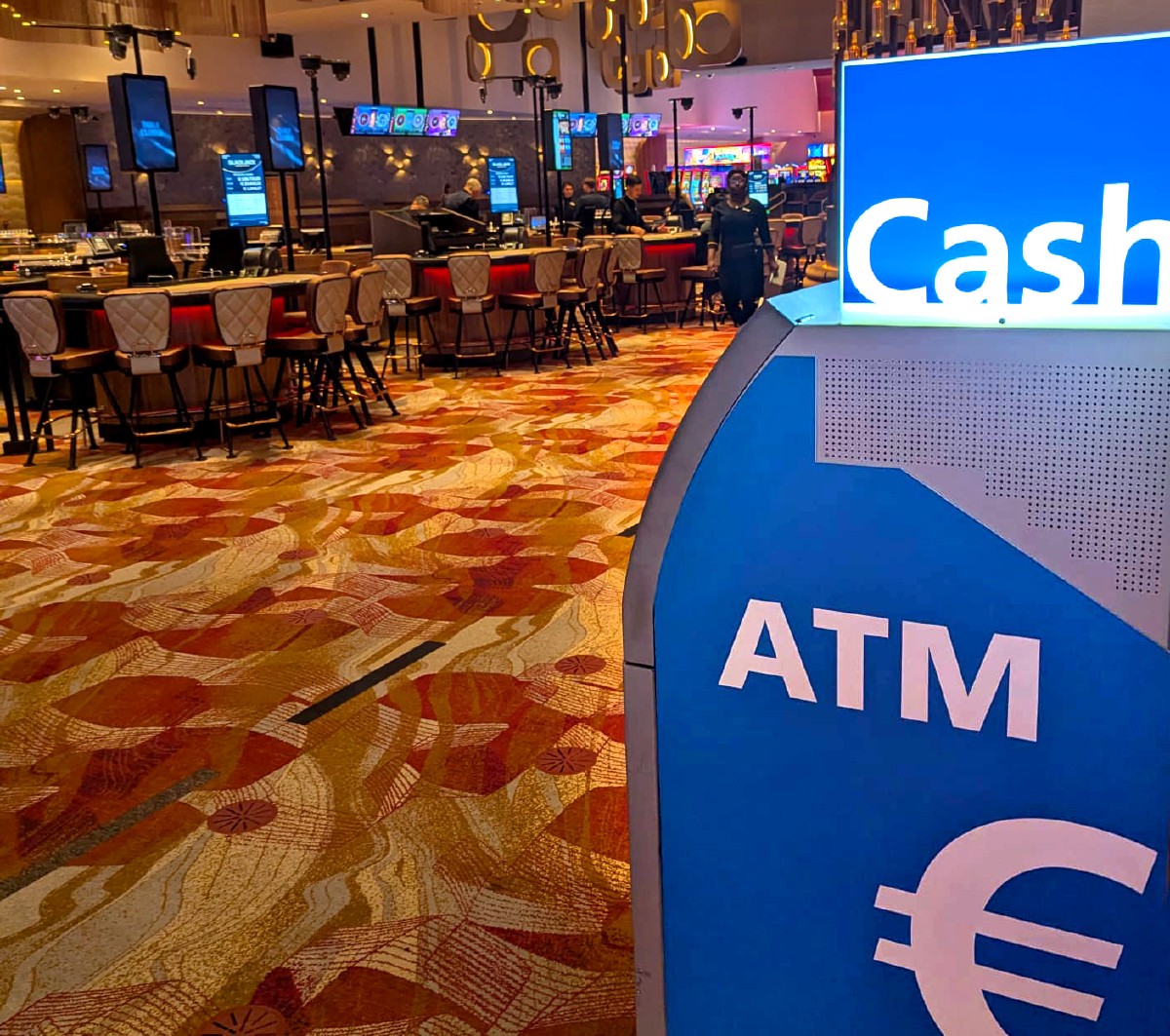 Geldautomat mit Blick auf den Spielbereich eines Casinos